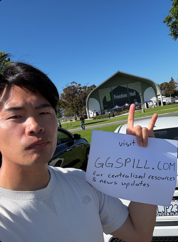 Victor at the Freedom Hall evacuation center holding a hand-written sign that reads visit GGSPILL.COM for centralized resources and news updates