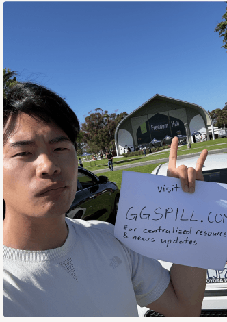 Victor at the Freedom Hall evacuation center holding a hand-written sign that reads visit GGSPILL.COM for centralized resources and news updates